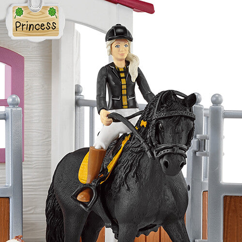 Close-up van de Schleich ruiterfiguur op het zwarte paard met een deel van de paardenbox op de achtergrond.