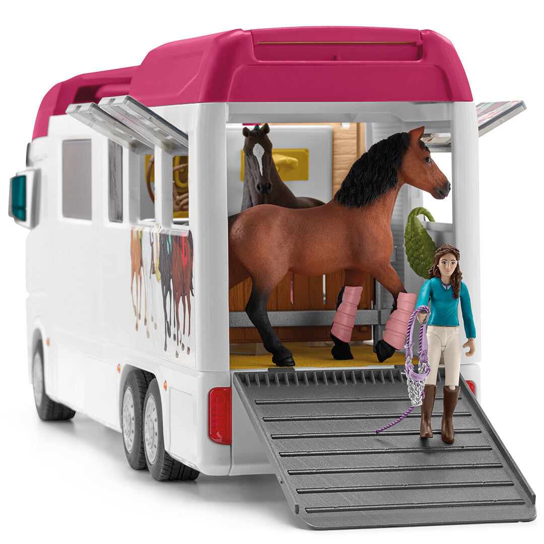 Schleich paardenvrachtwagen met een figuur die een bruin paard met roze beenbeschermers via de geopende laadklep uitlaadt.
