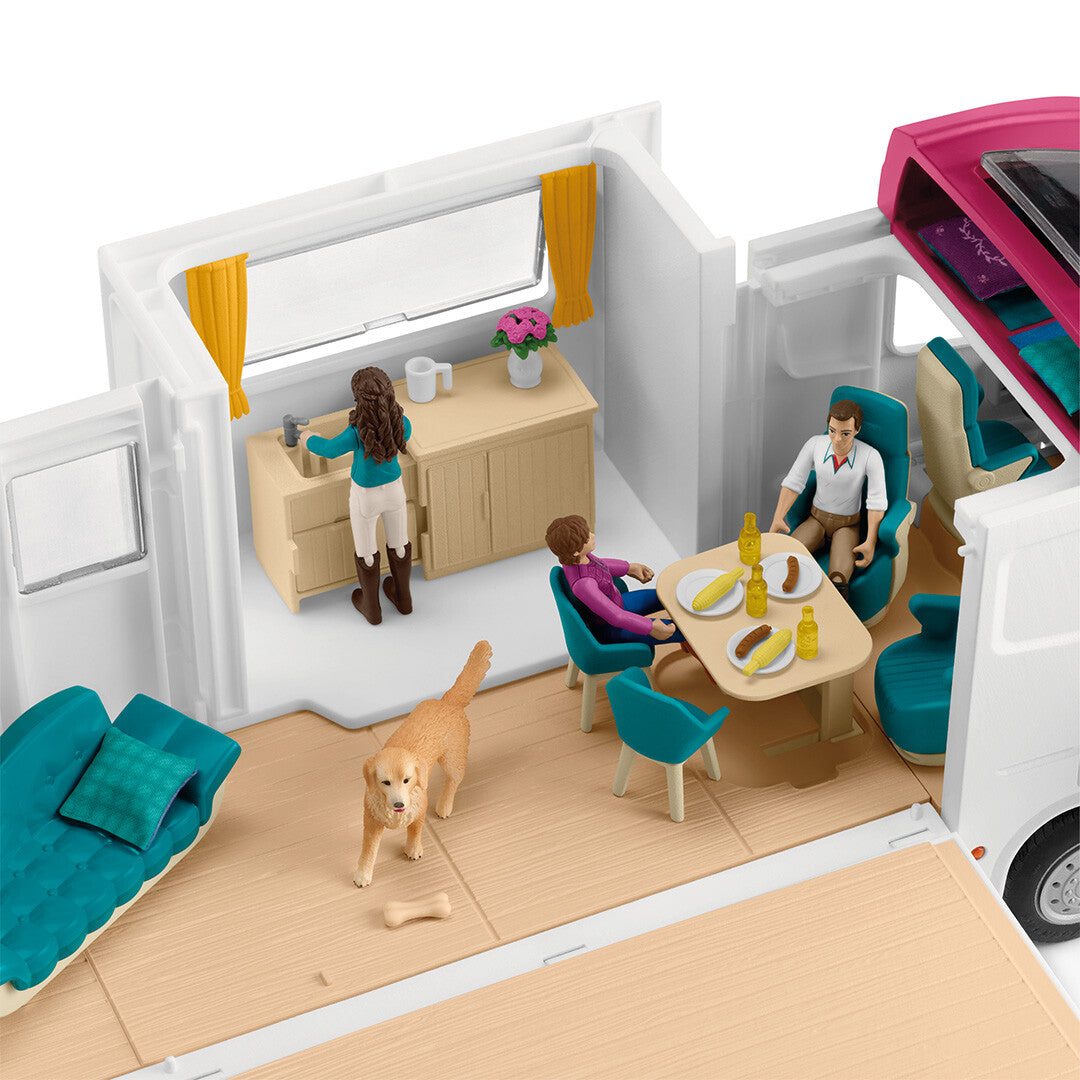 Interieur van de opengeklapte Schleich paardenvrachtwagen met een keuken, eethoek met figuren en een hond.