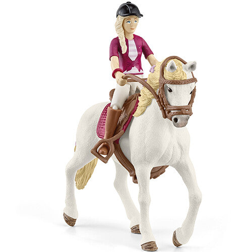 Schleich speelgoedfiguur van een meisje met blonde vlecht en zwarte cap op een wit paard met bruin zadel.