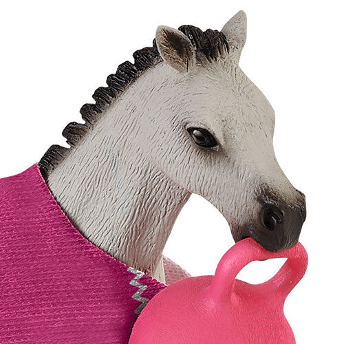 Detail van het Schleich veulen met roze deken dat een roze bal in de mond heeft.