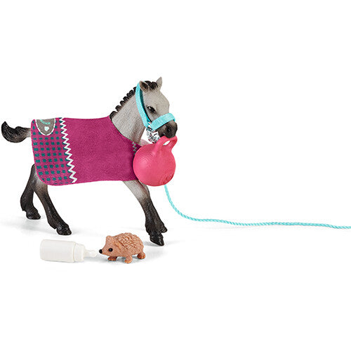 Schleich speelset met een grijs veulen met roze deken, blauw halster, een roze bal aan een touw, een egel en een flesje.