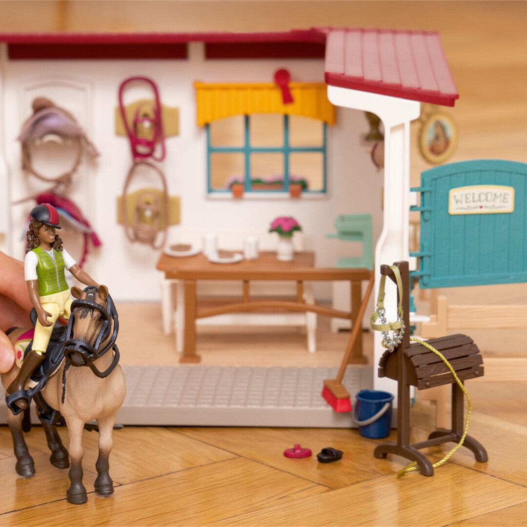 Detailfoto van de Schleich Horse Club zadelkamer speelset met een hand die de ruiter op het paard zet.