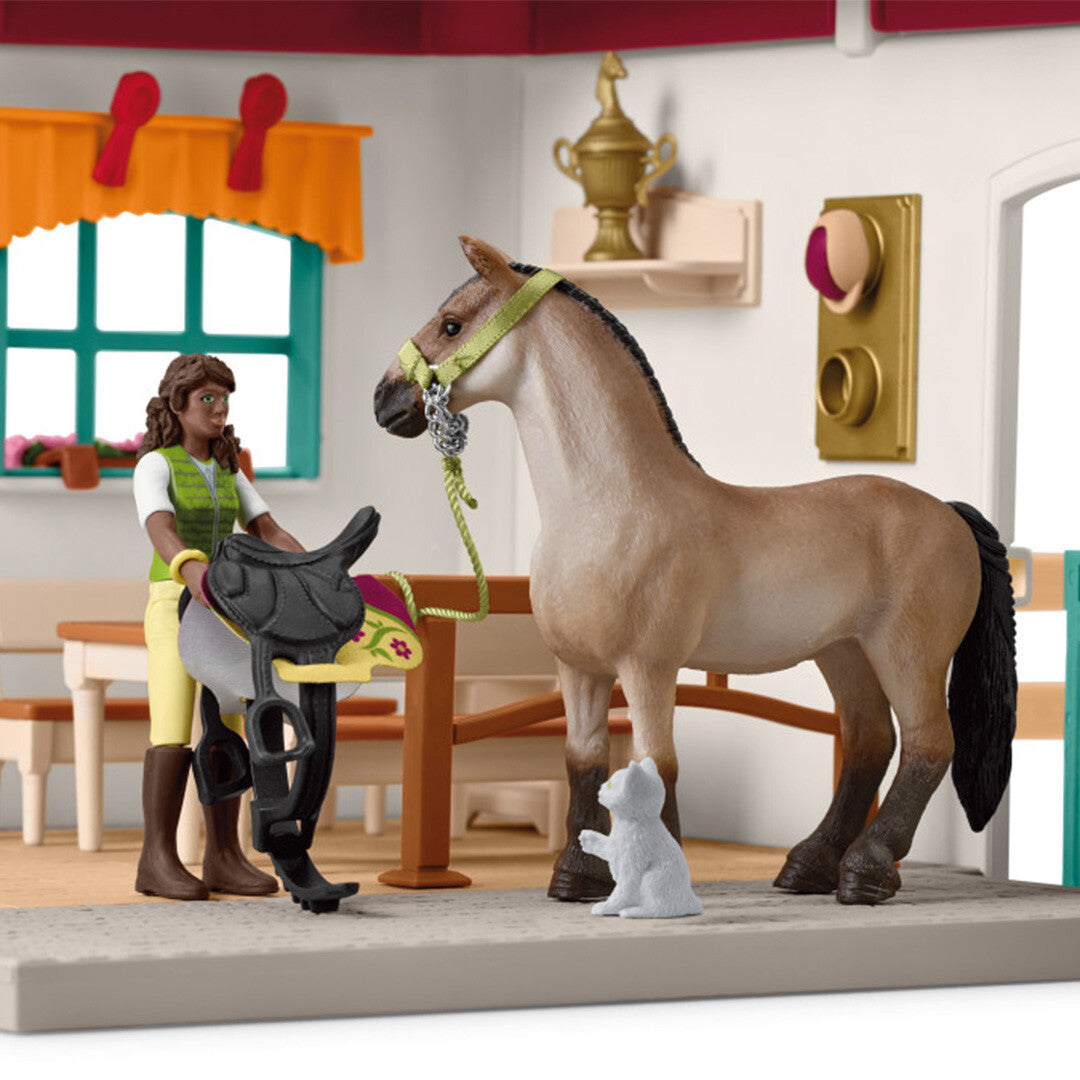 Detail van de zadelkamer speelset met een ruiterfiguur die een zadel vasthoudt naast een paard en een kat.