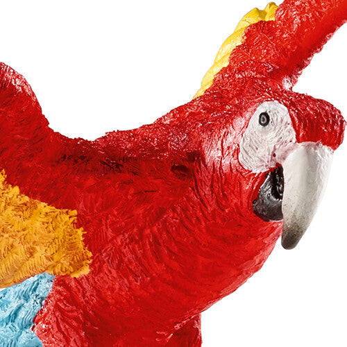 Detailopname van de kop en rode veren van het Schleich Wild Life ara speelgoedfiguur.