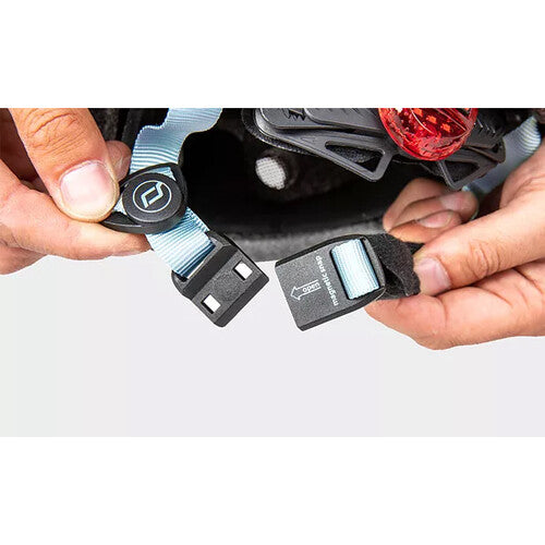 Twee handen demonstreren de magnetische sluiting van de kinband van de kinderhelm.