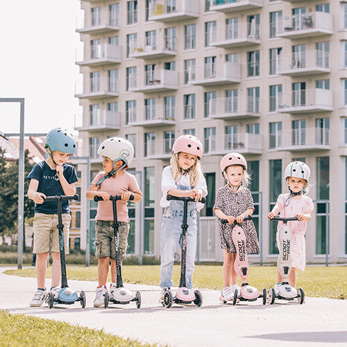 Vijf kinderen met helmen staan buiten met hun Scoot & Ride kindersteps in verschillende kleuren.