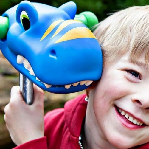 Een lachend kind met blond haar en rode hoodie naast het blauwe dinohoofd van de scootaheadz kinderstep accessoire.