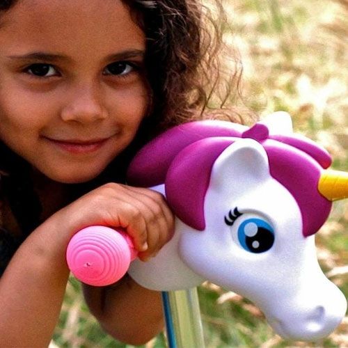 Een lachend meisje houdt het eenhoornhoofd kinderstep accessoire vast.