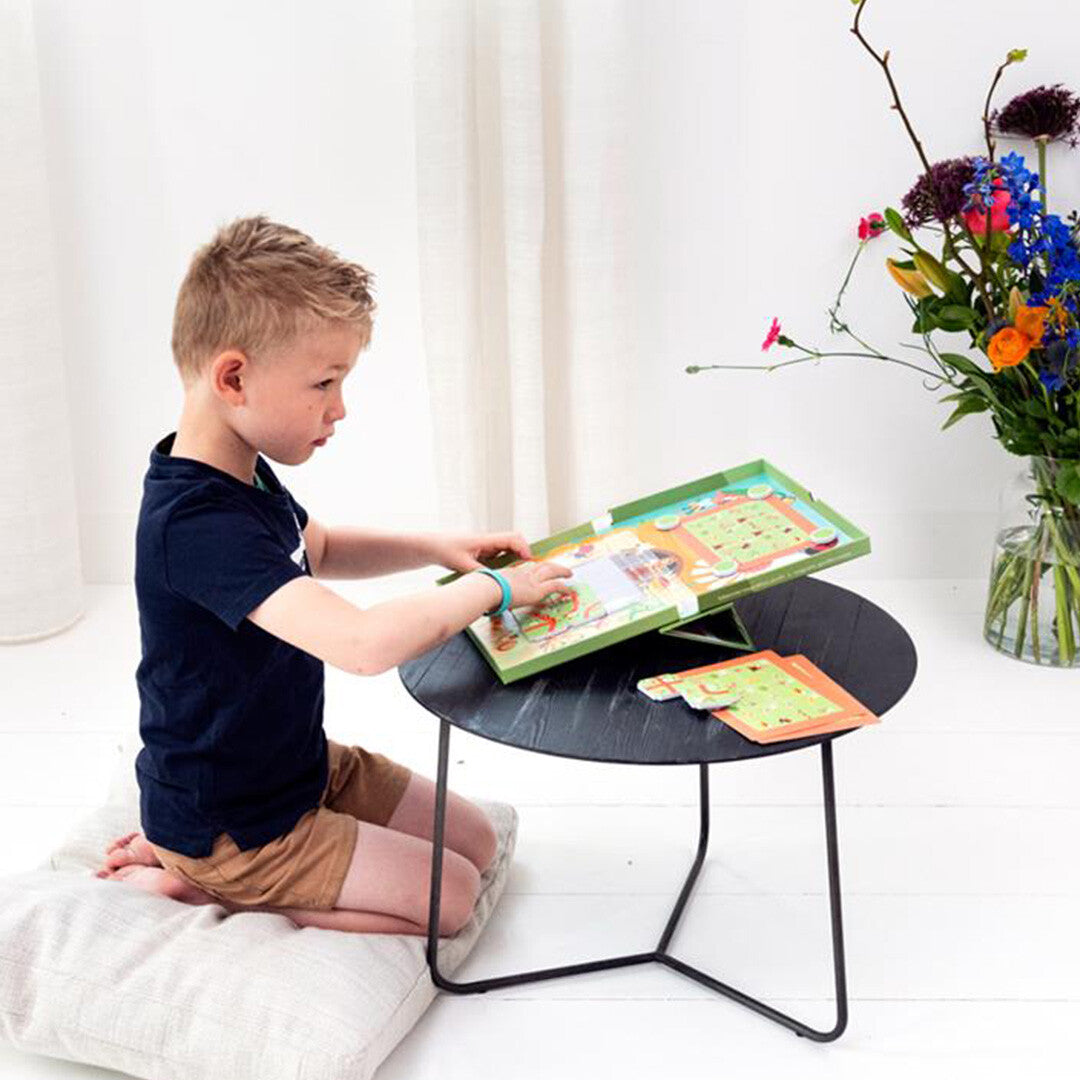 Een jongen speelt geconcentreerd met het Scratch Europe magnetisch doolhofspel aan een kleine tafel.