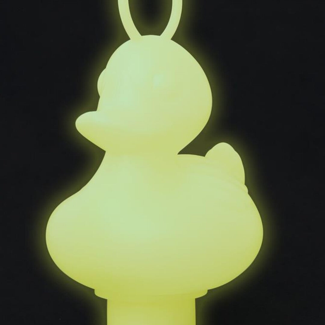 Een glow-in-the-dark badspeelgoed eendje met ring, lichtgevend tegen een donkere achtergrond.