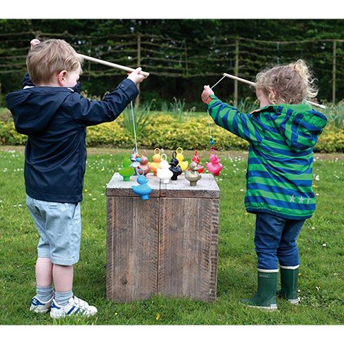 Twee kinderen vissen met houten hengels op kleurrijke eendjes die op een houten kist staan.