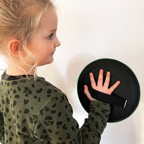 Een meisje houdt een zwarte vangschijf van het vangspel vast met haar hand door de band.