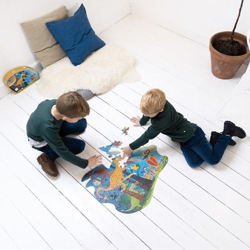 Twee kinderen leggen samen de Scratch Europe contour vloerpuzzel met draken en ridders op een witte vloer.
