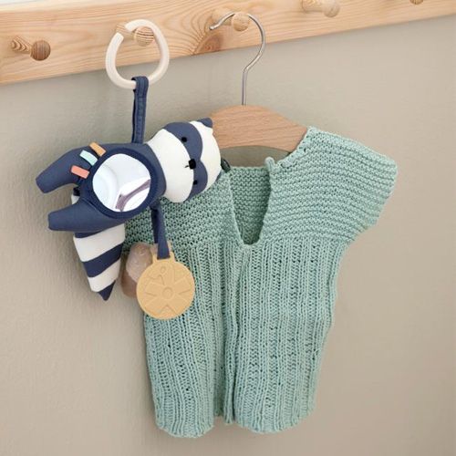Sebra activiteitenknuffel wasbeer hangend naast een groen gebreid babyvestje.