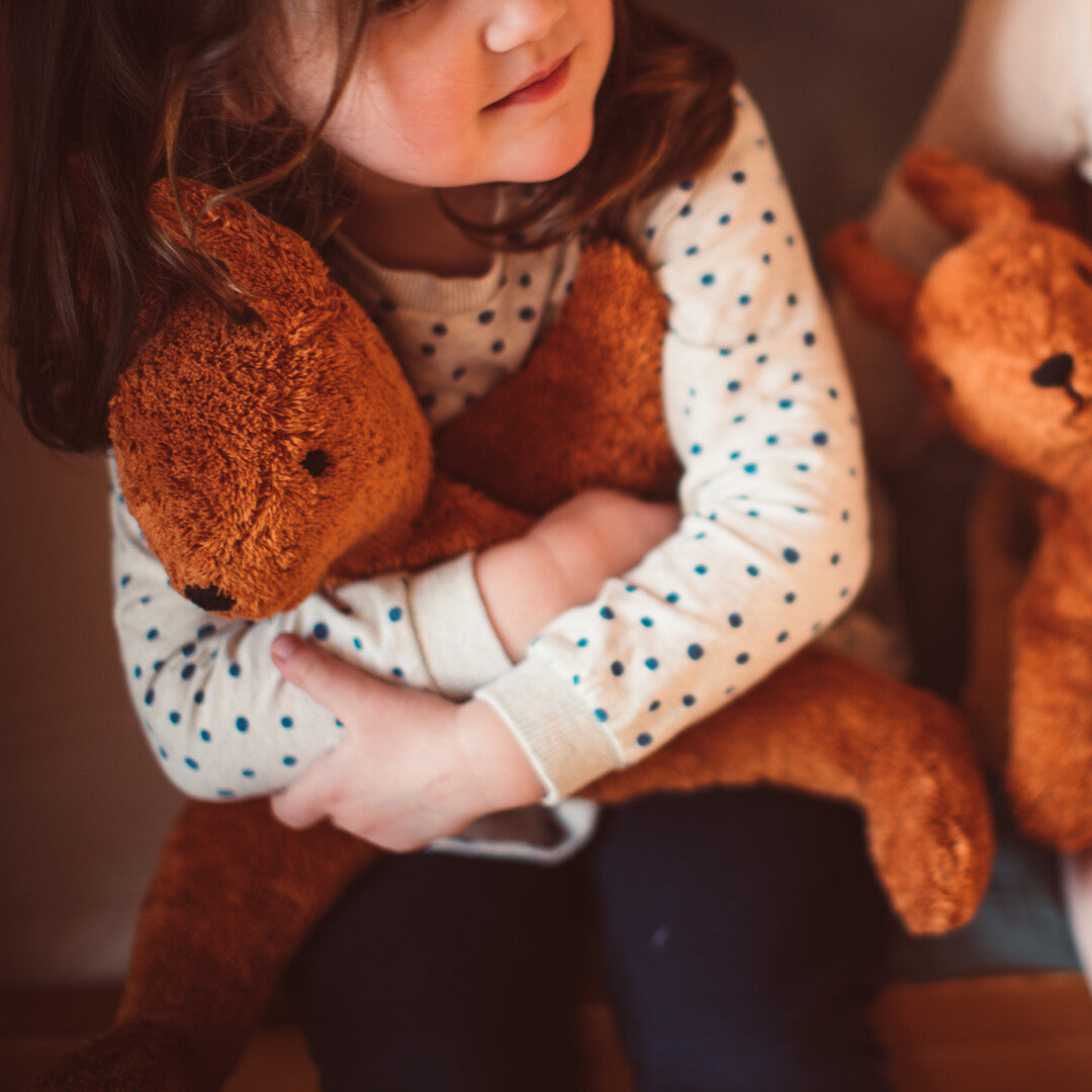 Een kind knuffelt de bruine Senger pluchen knuffeleekhoorn.