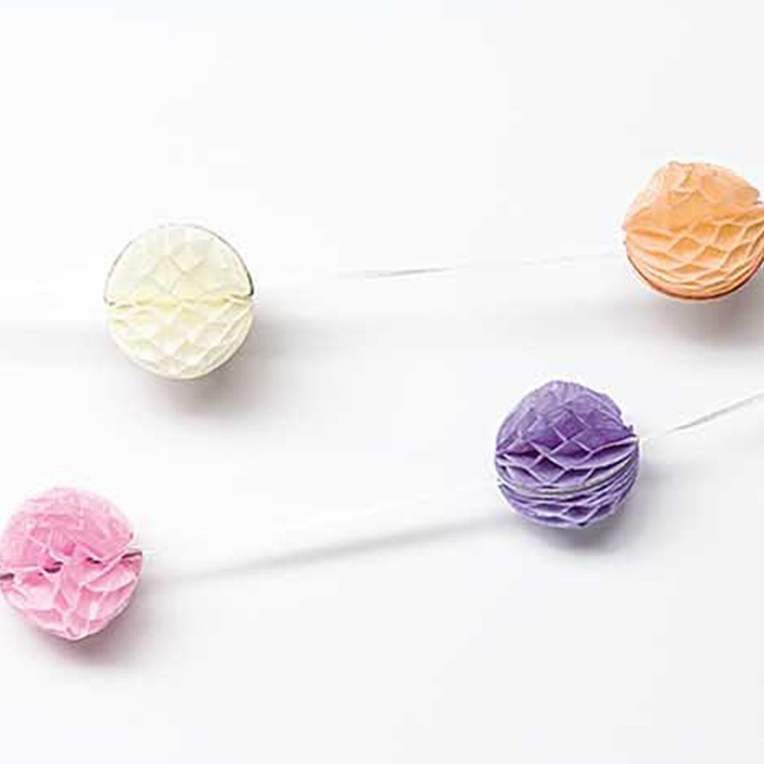 Close-up van vier pastelkleurige honingraat ballen van de Rico Design slinger.
