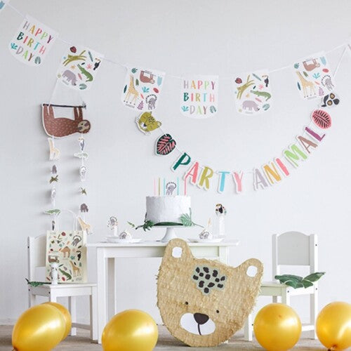 Demonstratie van de 'Happy Birthday' en 'Party Animal' slingers in een feestelijke kamer met een piñata en ballonnen.