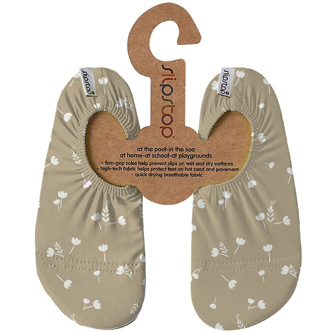 Slipstop baby- en peutersportschoenen in beige met wit bloemenpatroon, aan een kartonnen hanger.
