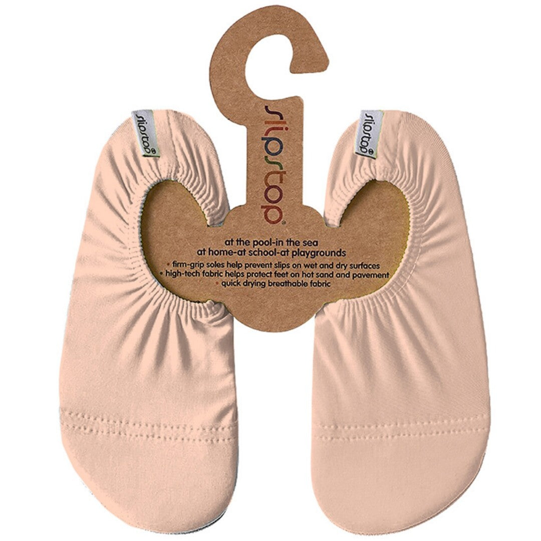 Twee zalmroze Slipstop baby- en peuterschoenen op een kartonnen hanger.