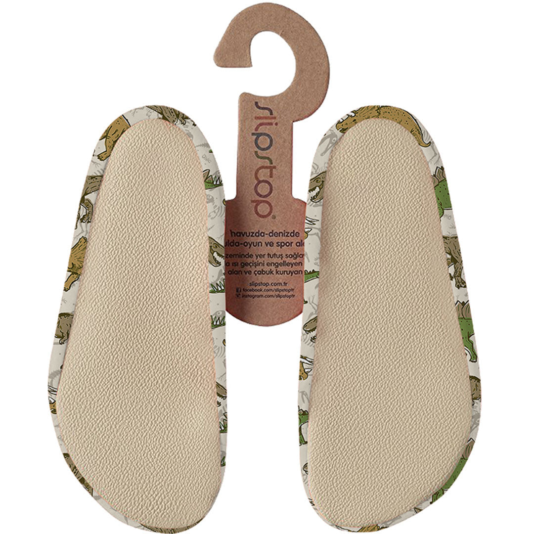 De onderkant van Slipstop waterschoentjes voor baby's en peuters met een beige dinosauruspatroon, waarop de antislipzolen zichtbaar zijn.