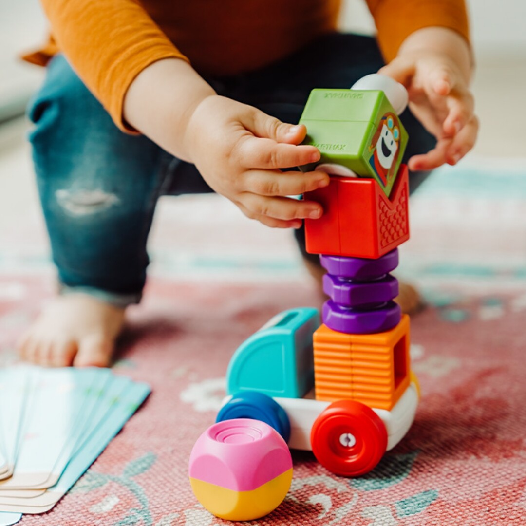 Kinderhanden bouwen een hoge constructie met kleurrijke Smartmax My First magnetische bouwblokken op een voertuigonderstel.