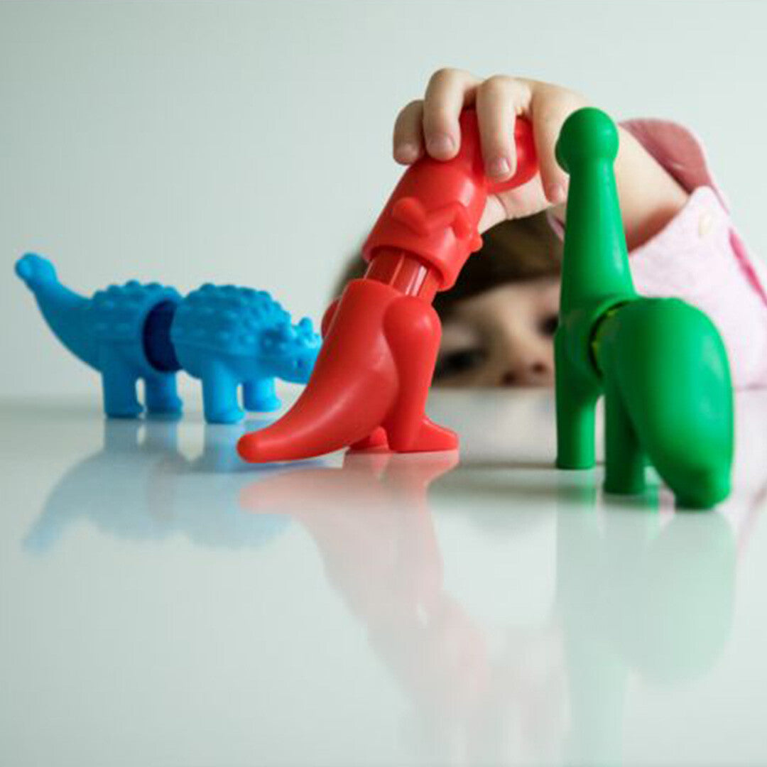 Een kind speelt met de Smartmax magnetische dinosaurusfiguren op een witte tafel.