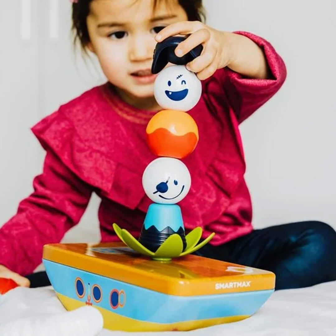 Een kind stapelt de piratenfiguren van het SmartMax My First Piraten magnetisch puzzelspel op een schip.