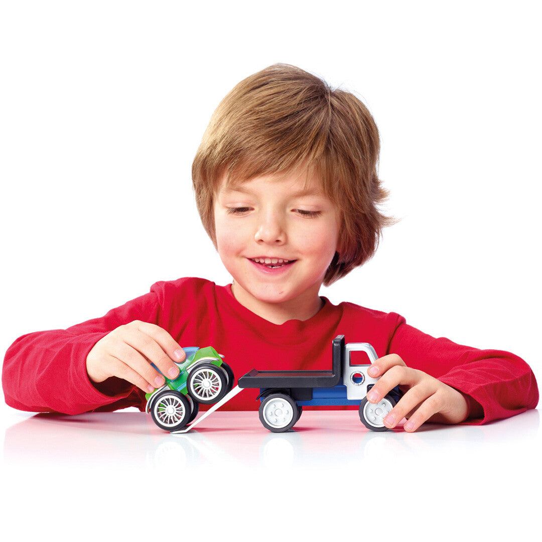Een lachend kind speelt met een SmartMax magnetische vrachtwagen en laadt een groen voertuig op de laadklep.