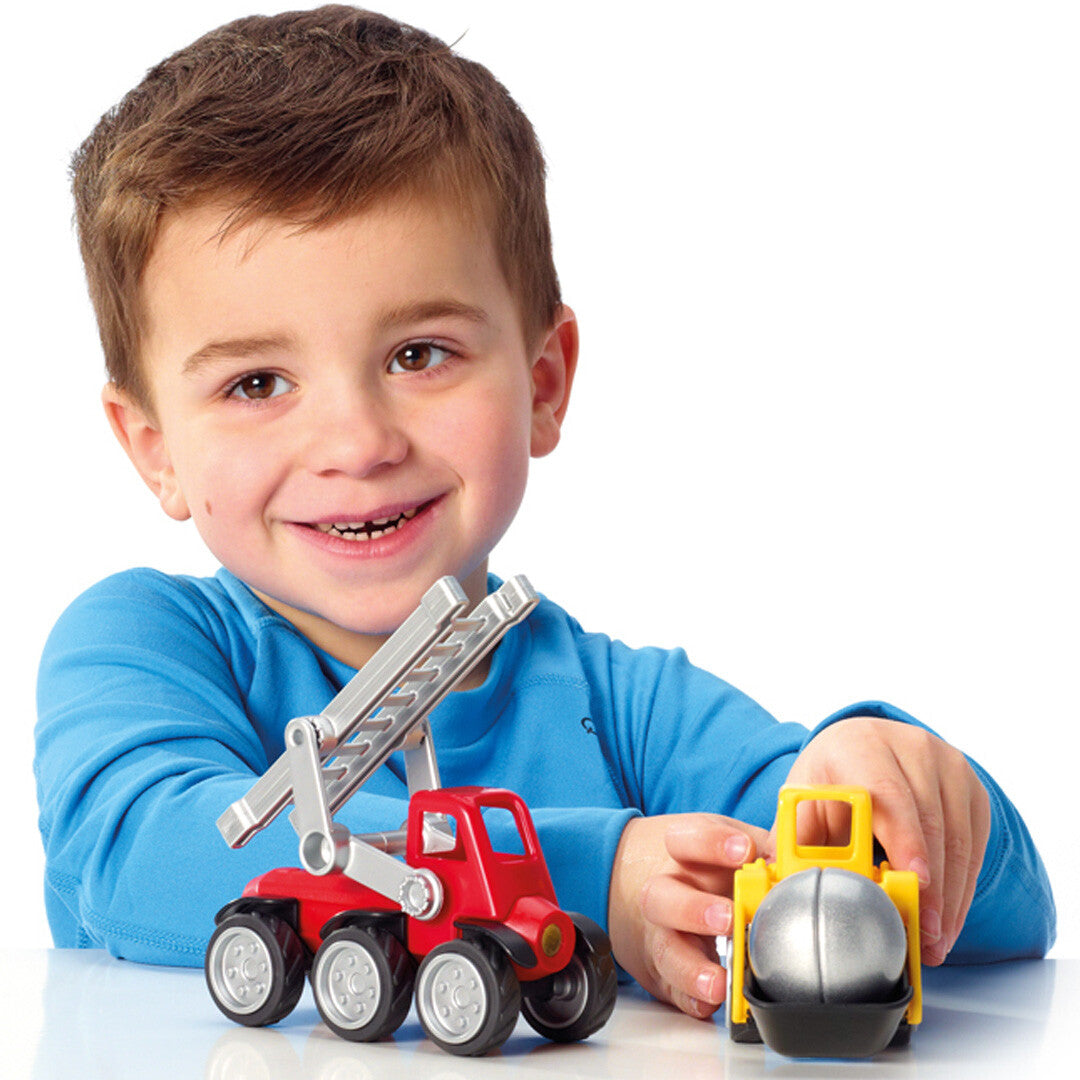Een lachend kind speelt met twee SmartMax magnetische bouwvoertuigen, een rode ladderwagen en een gele sloopwagen.