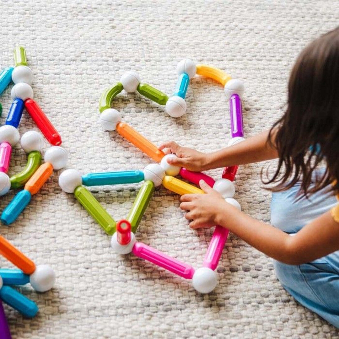 Kinderhanden bouwen met kleurrijke SmartMax magnetische bouwblokken op een tapijt.