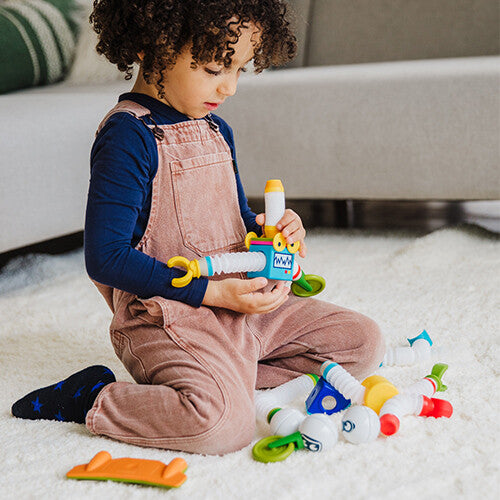 Een kind zit op de grond en speelt met een SmartMax magnetische bouwset.