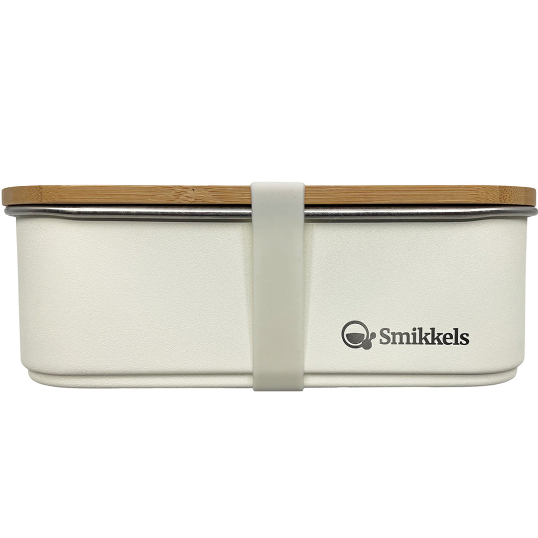 Smikkels RVS broodtrommel voor kinderen in crème met bamboe deksel en siliconen band, vooraanzicht.