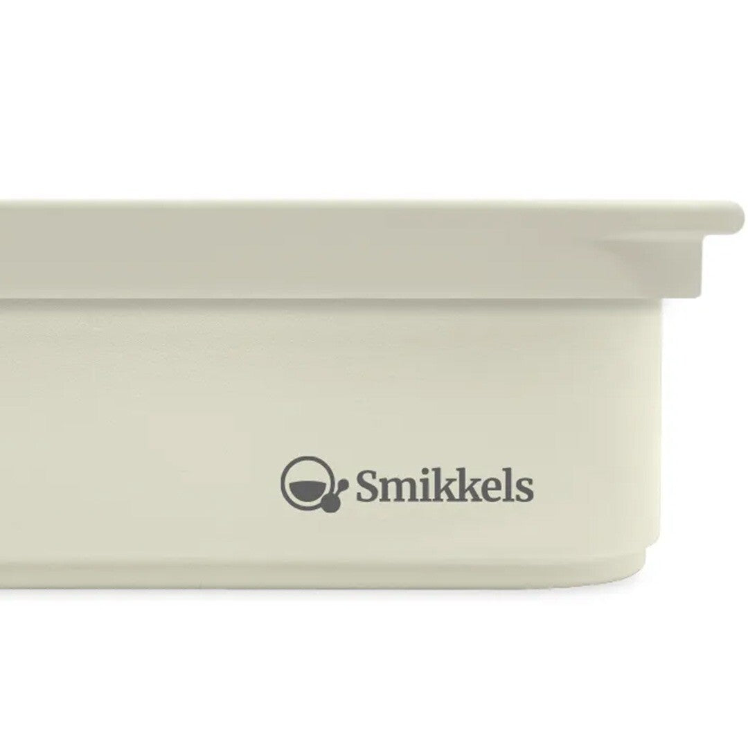 Detail van de Smikkels RVS broodtrommel in crème kleur, met het Smikkels logo op de voorkant.