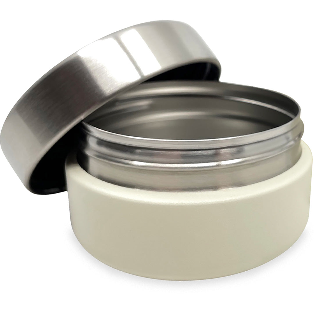 Open Smikkels rvs voedselpot crème met het zilverkleurige deksel ernaast.