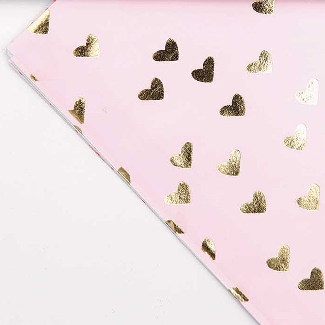 Detail van roze papier met gouden hartjespatroon.