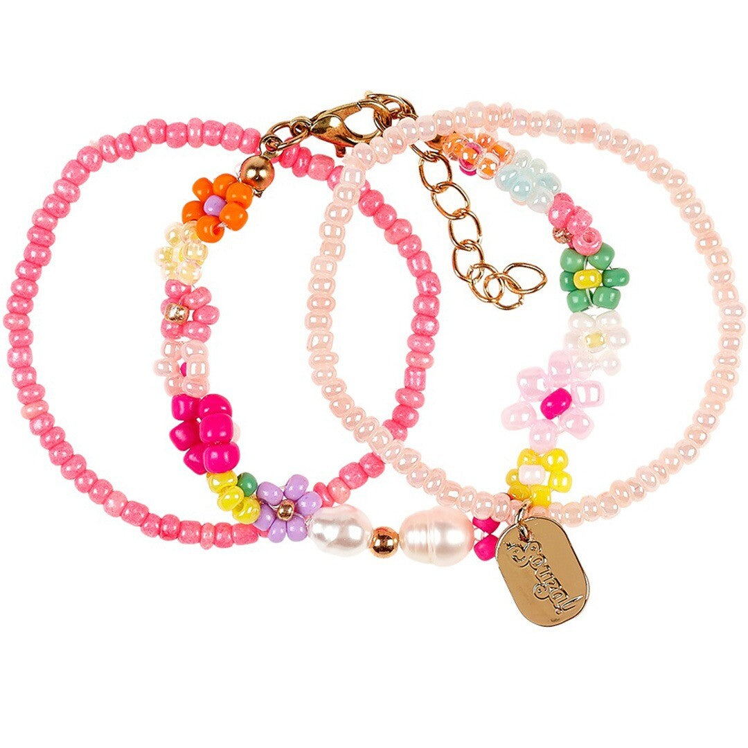 Drie roze en lichtroze Souza for Kids kinderarmbanden met bloemenkralen, parels en een goudkleurige bedel.