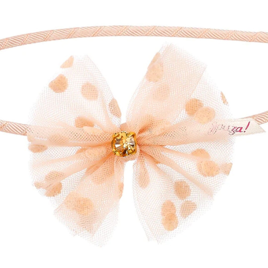 Detail van de roze strik met stippen en een kristal op de kinder hoofdband.