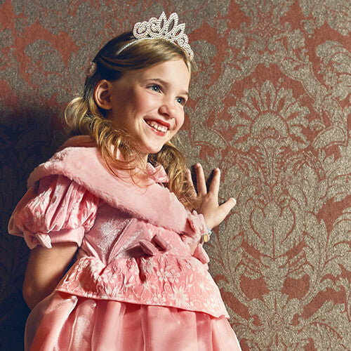 Lachend meisje draagt de Souza for Kids roze diadeem en een prinsessenjurk.