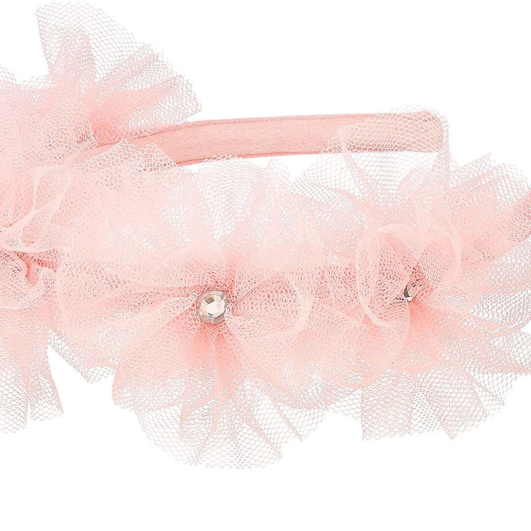 Detailopname van de roze kinder hoofdband met bloemen van tule en kristallen.