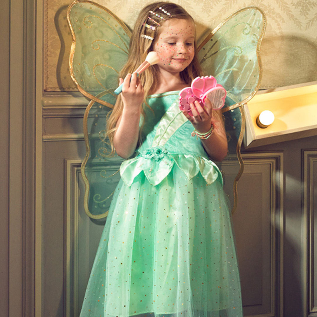 Een meisje in de Souza for Kids elfenjurk Camille met vleugels, die make-up opdoet.