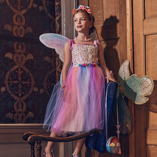 Meisje poseert in de Souza for Kids elfenjurk Felicity met regenboogrok, pailletten top en vleugels.