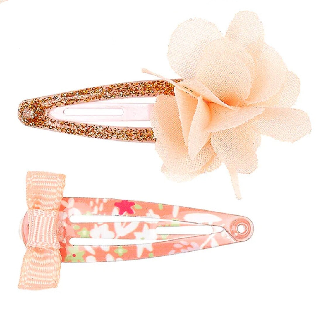 Twee Souza for Kids oranje haarspeldjes voor kinderen, één met glitter en een stoffen bloem, en één met een gebloemd patroon en een strikje.