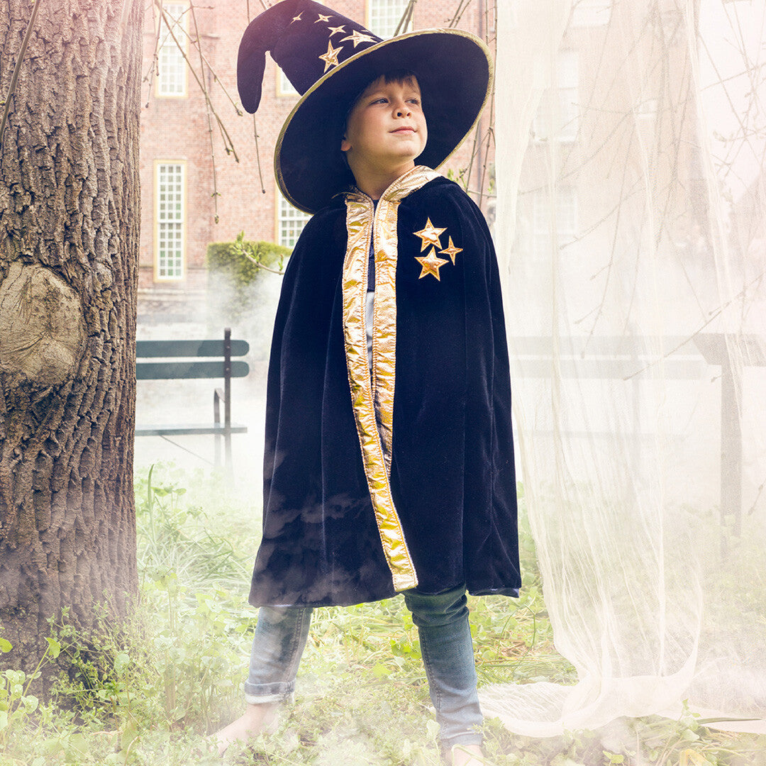 Kind draagt een Souza for Kids tovenaarshoed en cape met sterren in een mistige tuin.