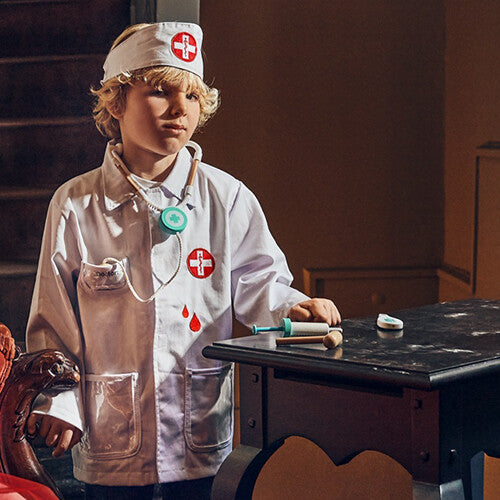 Een jongen draagt de souza for kids verkleedset dokter met witte doktersjas en muts, en een stethoscoop.