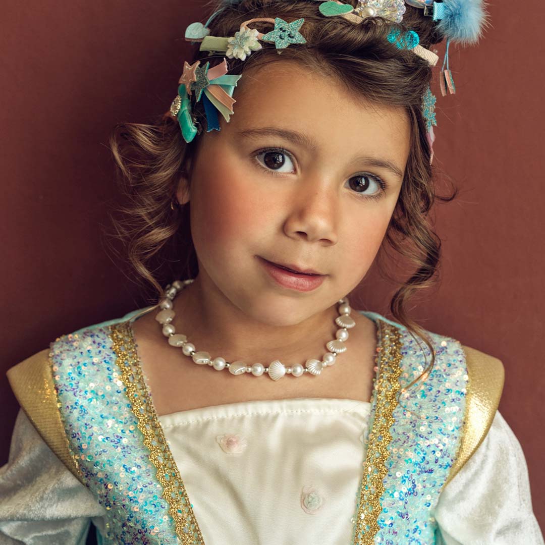 Detail van het bovenlijf van de prinsessen verkleedjurk met pailletten en een parelketting om de nek van het meisje.