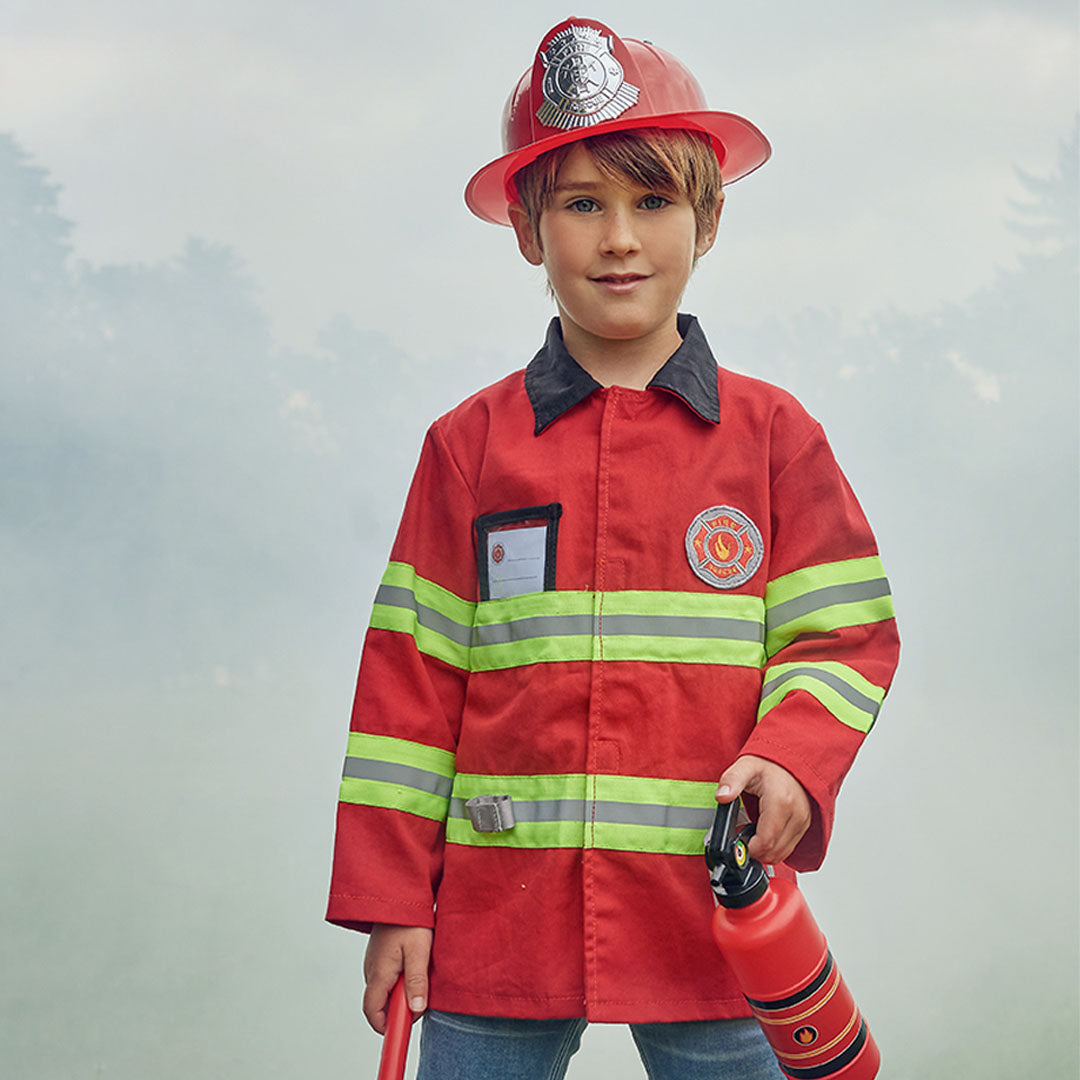 Een jongen draagt de Souza for Kids brandweer verkleedkleding met rode jas en helm, en houdt een speelgoedbrandblusser vast.