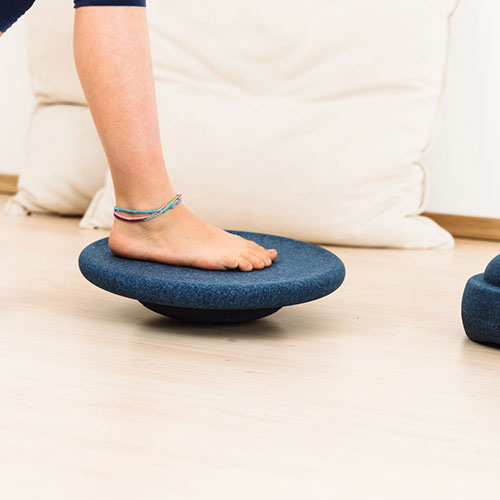 Een kind staat met blote voet op een Stapelstein balance board in schemerblauw.