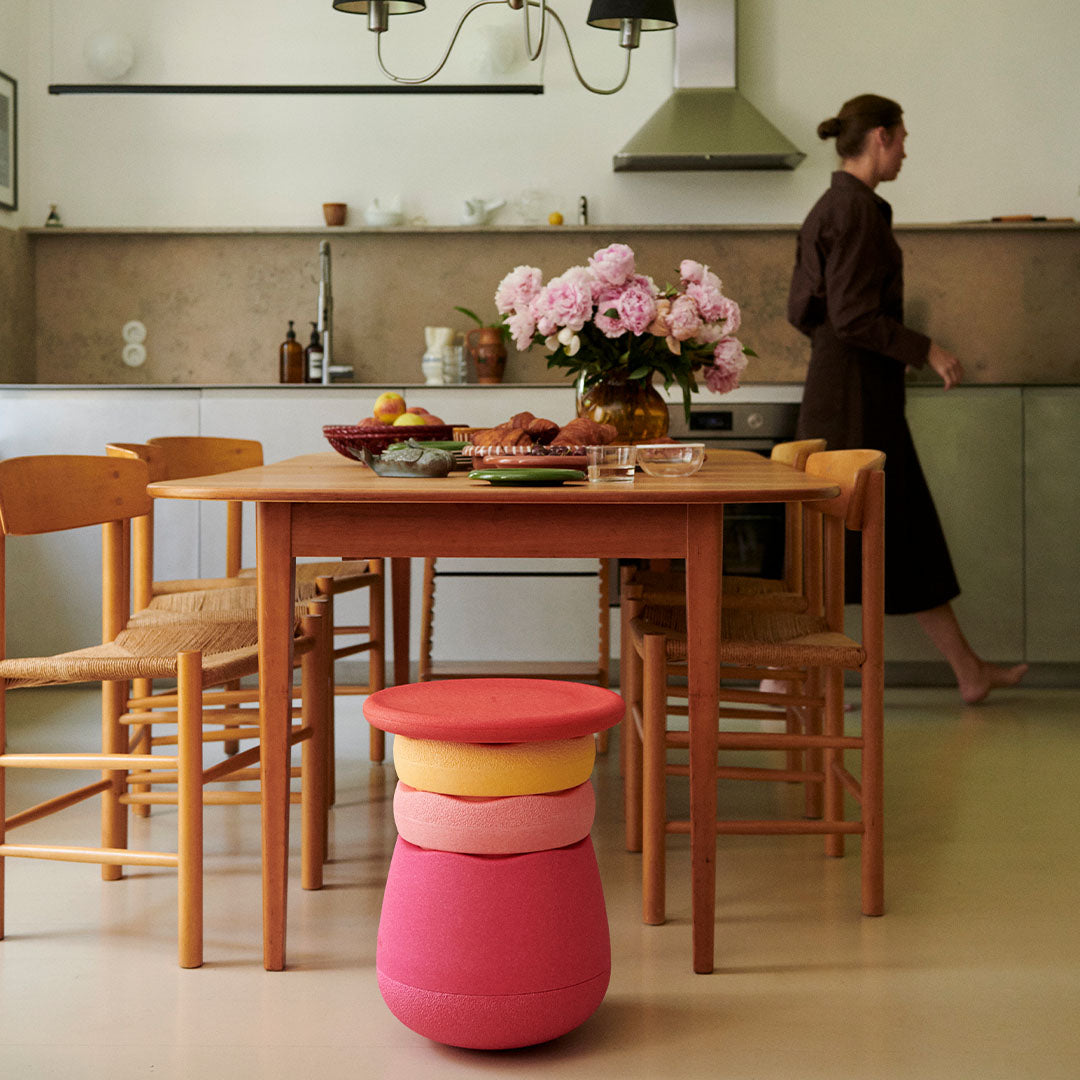 Een stapel Stapelstein dynamic flowers schuimrubberblokken staat als krukje naast een houten eettafel in een keuken.