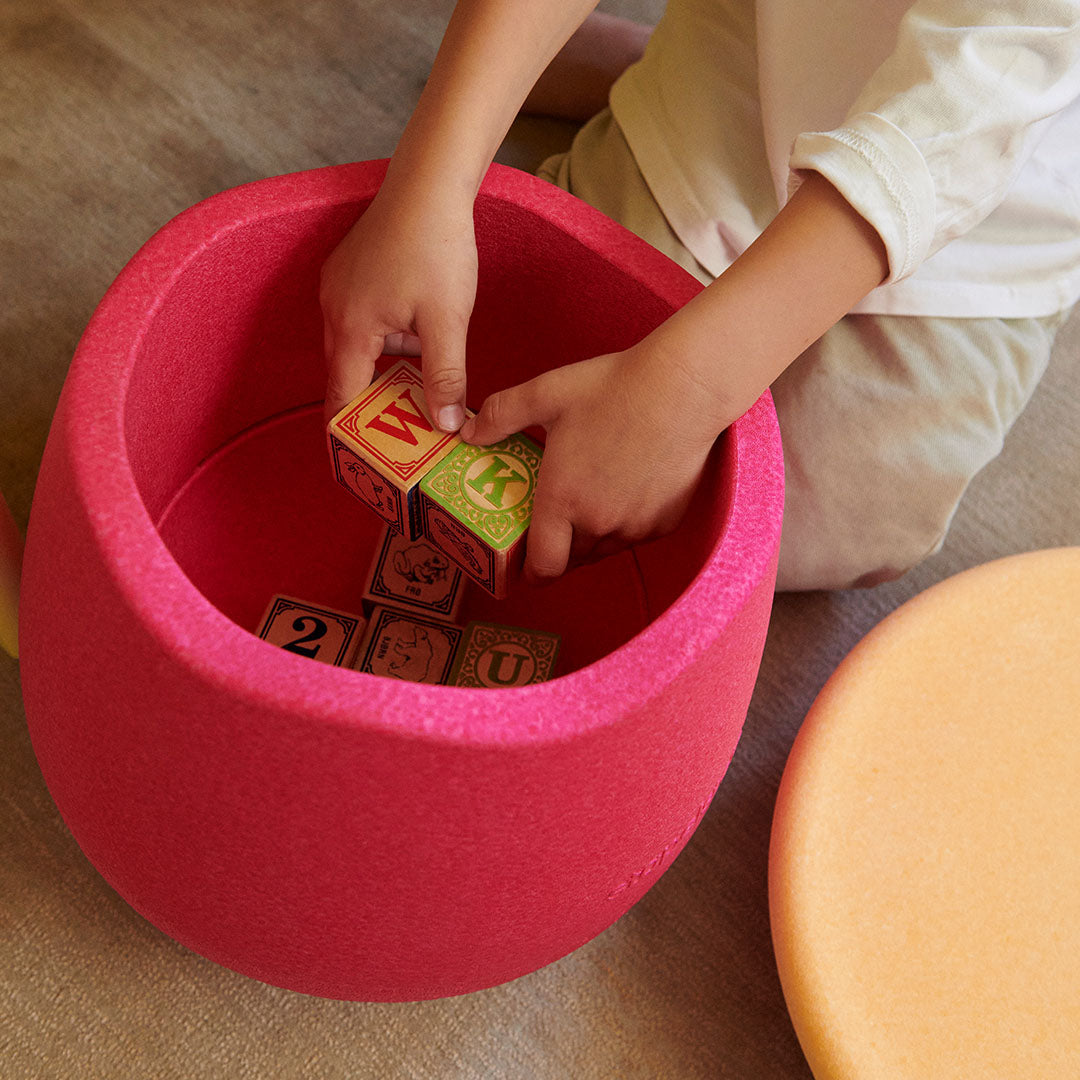 Handen plaatsen houten blokken in een open roze stapelstein dynamic small.